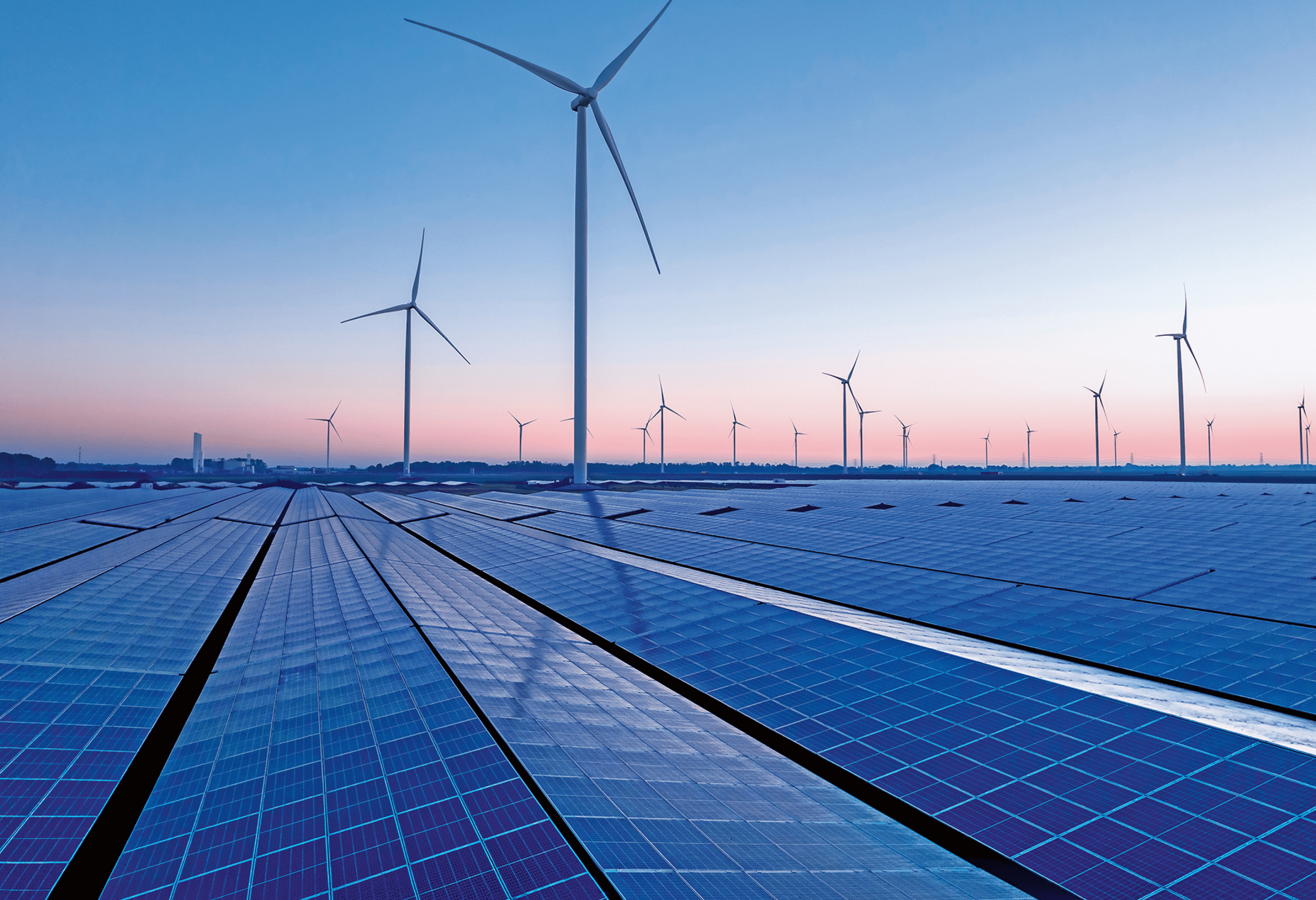 Wind turbines and solar panels at sunset